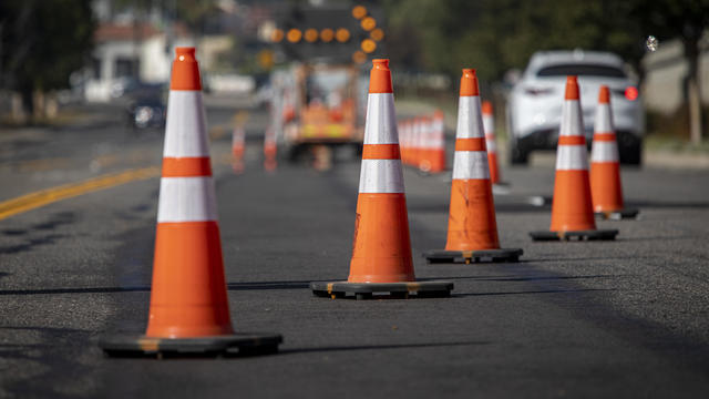 Lane closure on a busy road due to maintenance signs detour traffic temporary street work orange lighted arrow, barrels, and cones. 