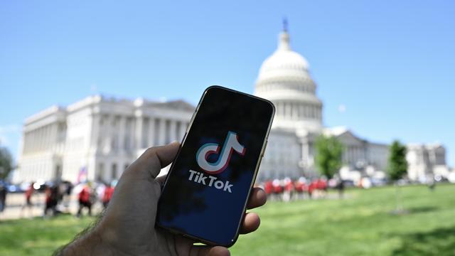 The logo of TikTok is displayed on a mobile phone screen in front of The White House in Washington DC, United States on April 20, 2024. 